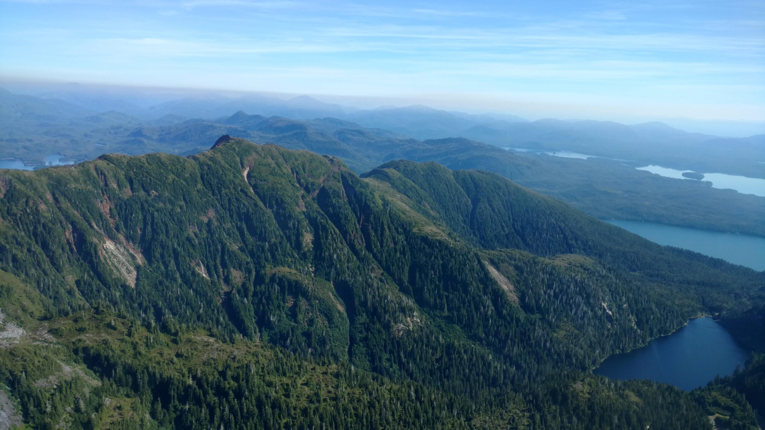 Ariel View of Misty Fjords in Ketchikan Alaska Tongass National Forest. Glacier fed lake on the top of a mountain with dense forests surrounding it.