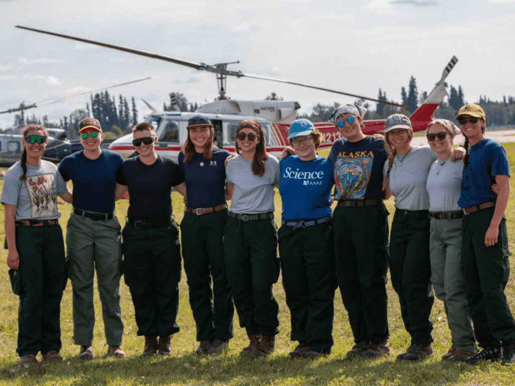Alaska All Women's Team standing in front of helicopter