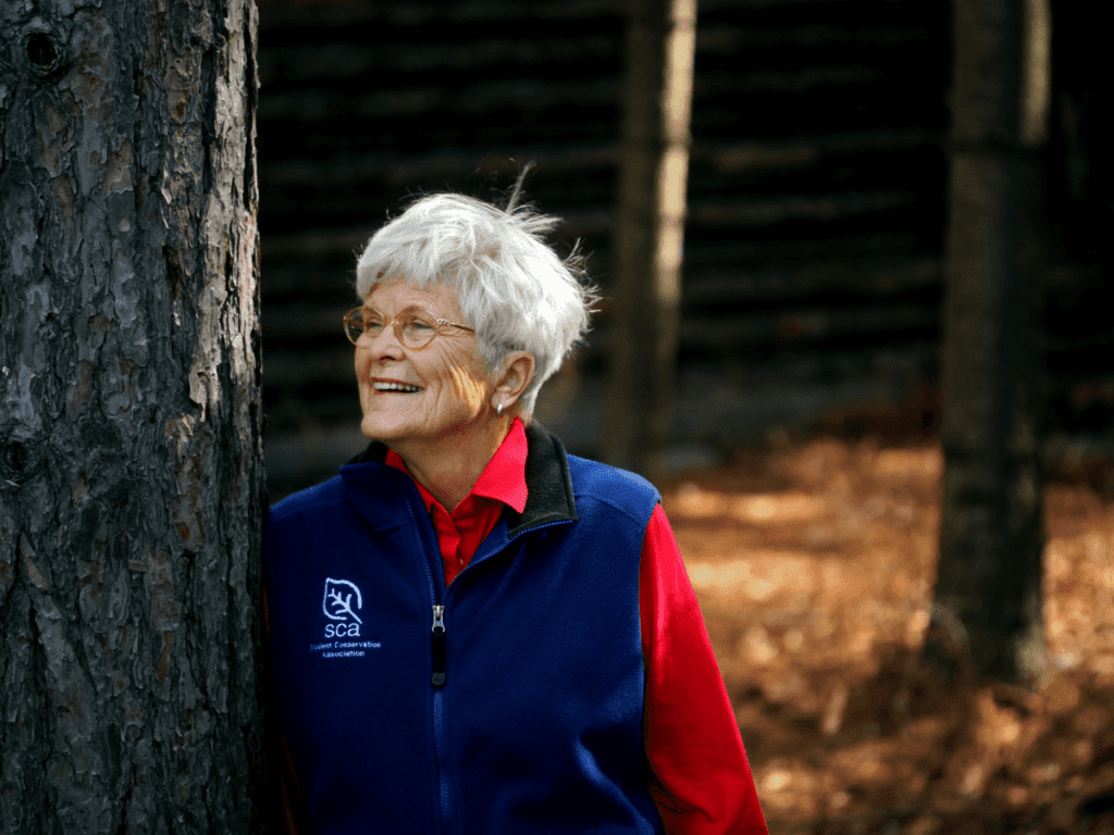 SCA Founder Liz Putnam smiling in a blue vest and red shirt
