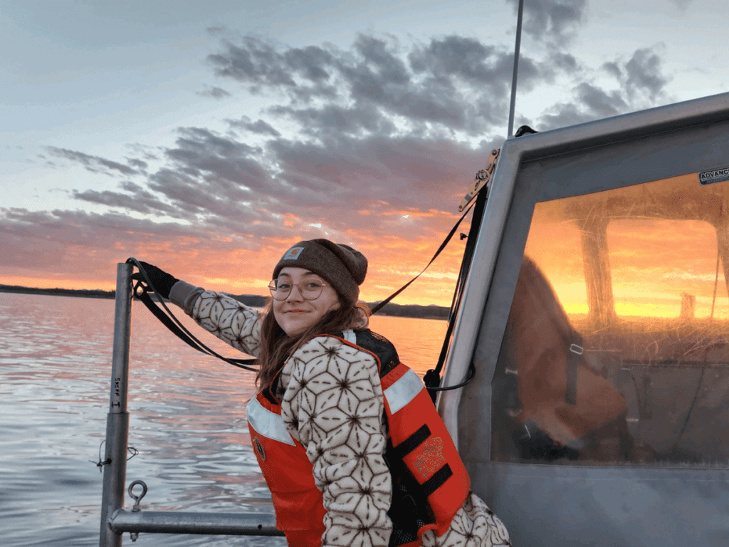 SCA intern on boat with sunrise 
