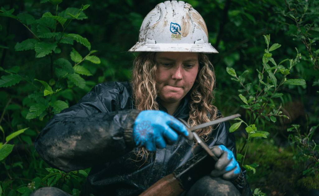 Olympic National Park Backcountry Team Member Gracey Michaelis sharpening a tool 