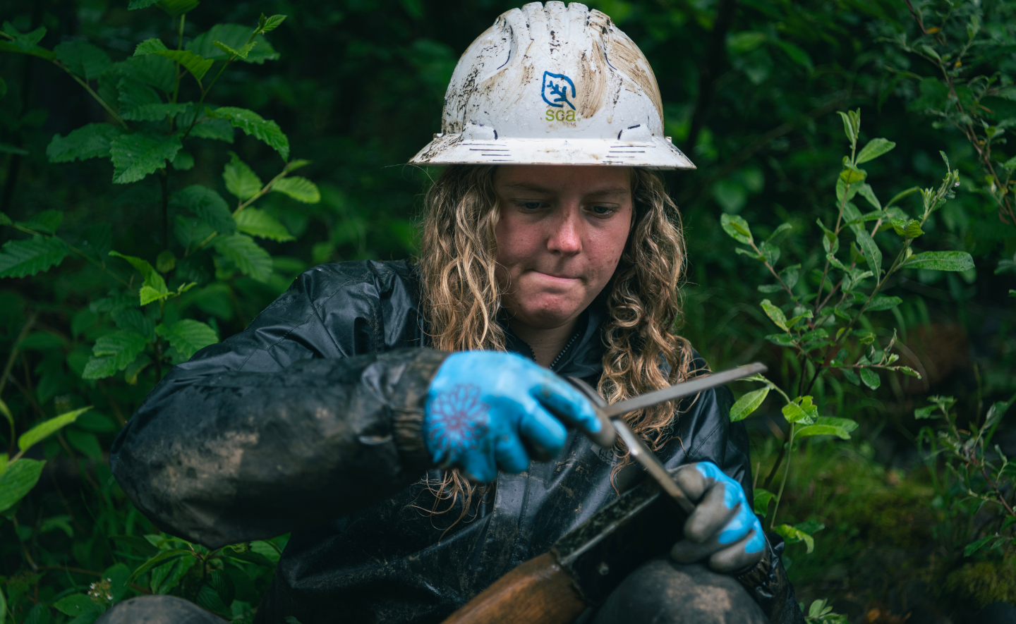 Olympic National Park Backcountry Team Member Gracey Michaelis sharpening a tool