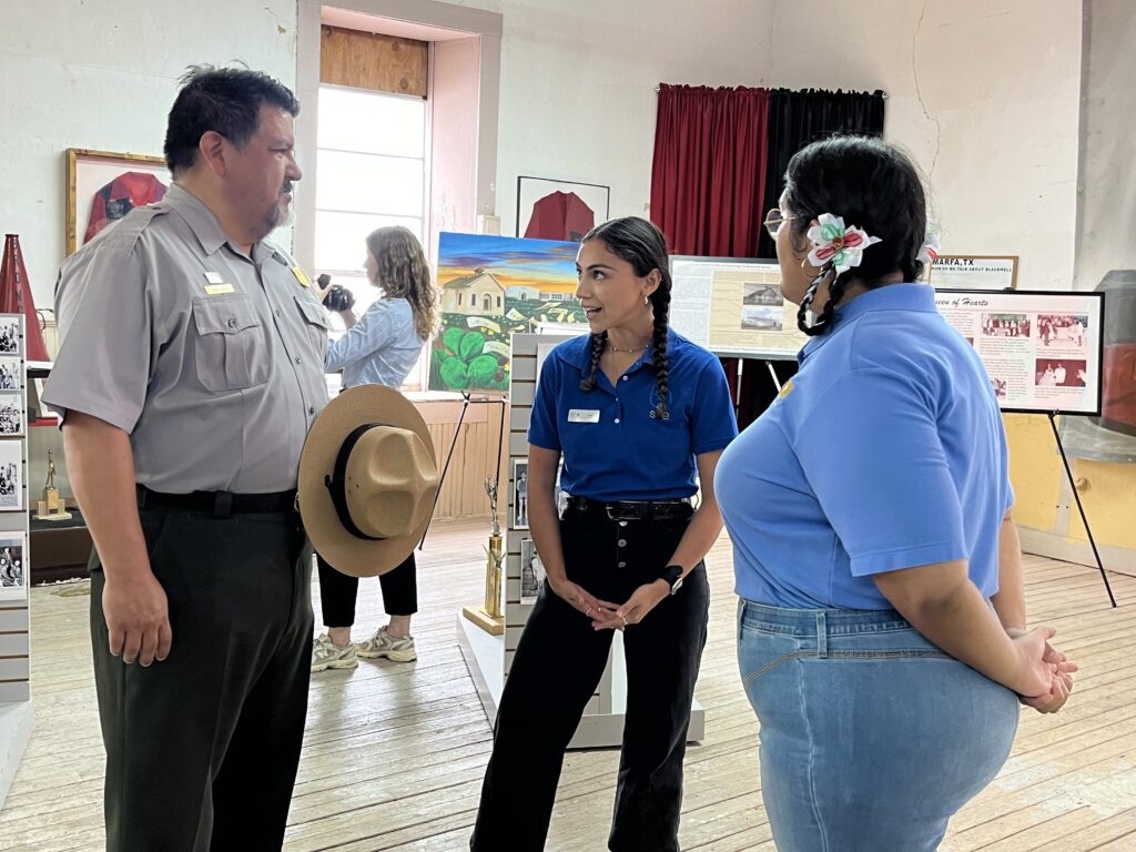 NPS Dir. Chuck Sams and another staffer stand with SCA intern Victoria Villarreal as she gives a tour of the Blackwell School.